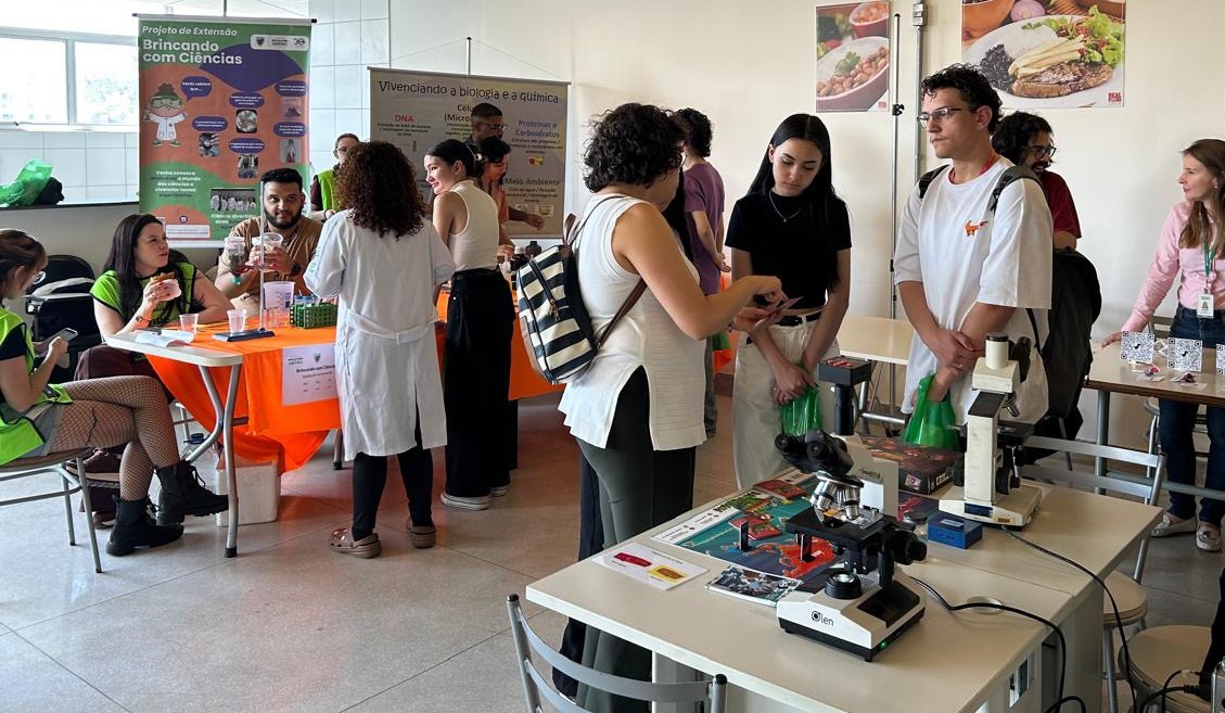 Estande "Brincando com Ciências" com demonstração de microscópio na II edição, em 2025